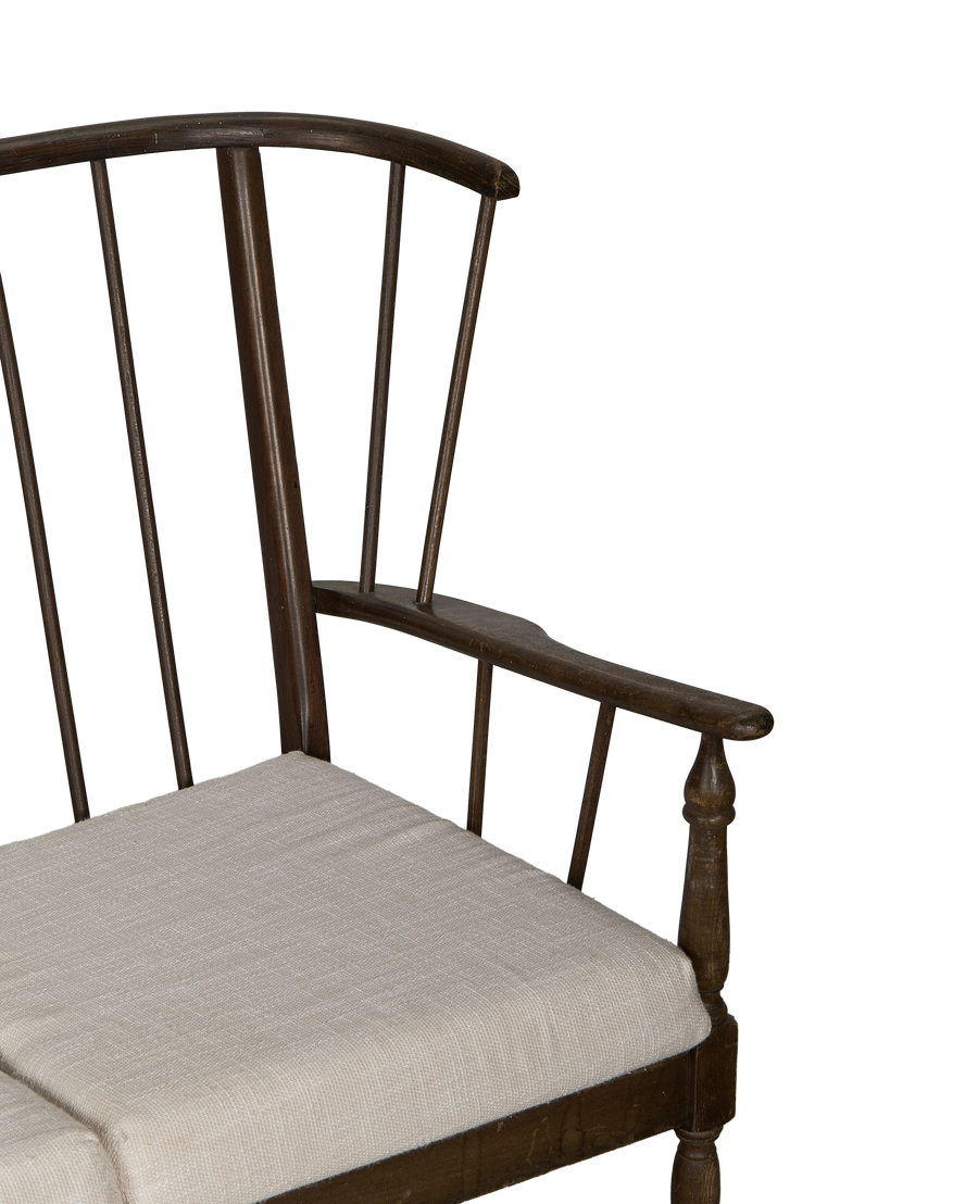Close-up: Vintage French oak lounge bench, linen cushion, and spindle back detail.