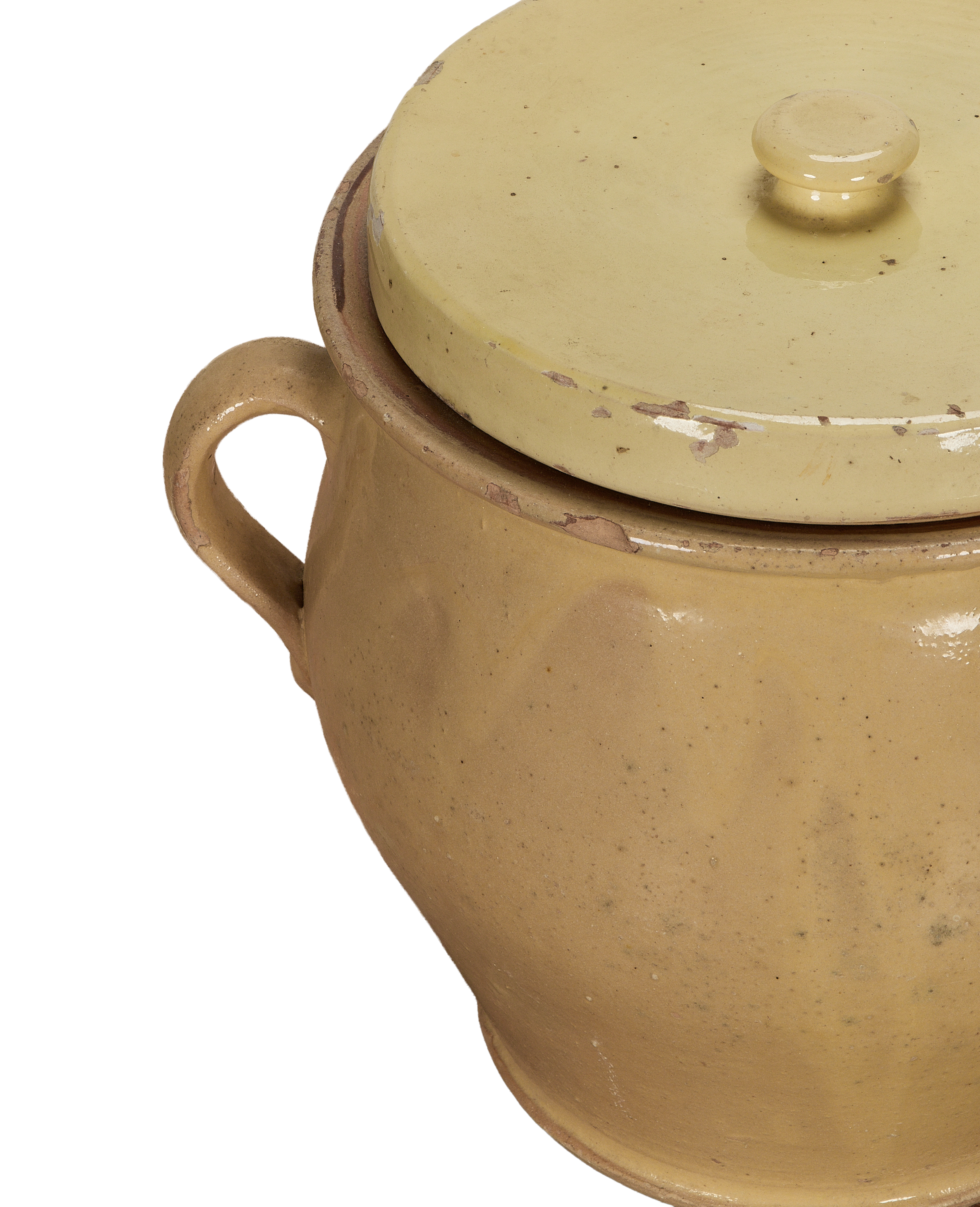 Close-up of antique French confit pot's yellow glazed lid with chipped rim and handle.