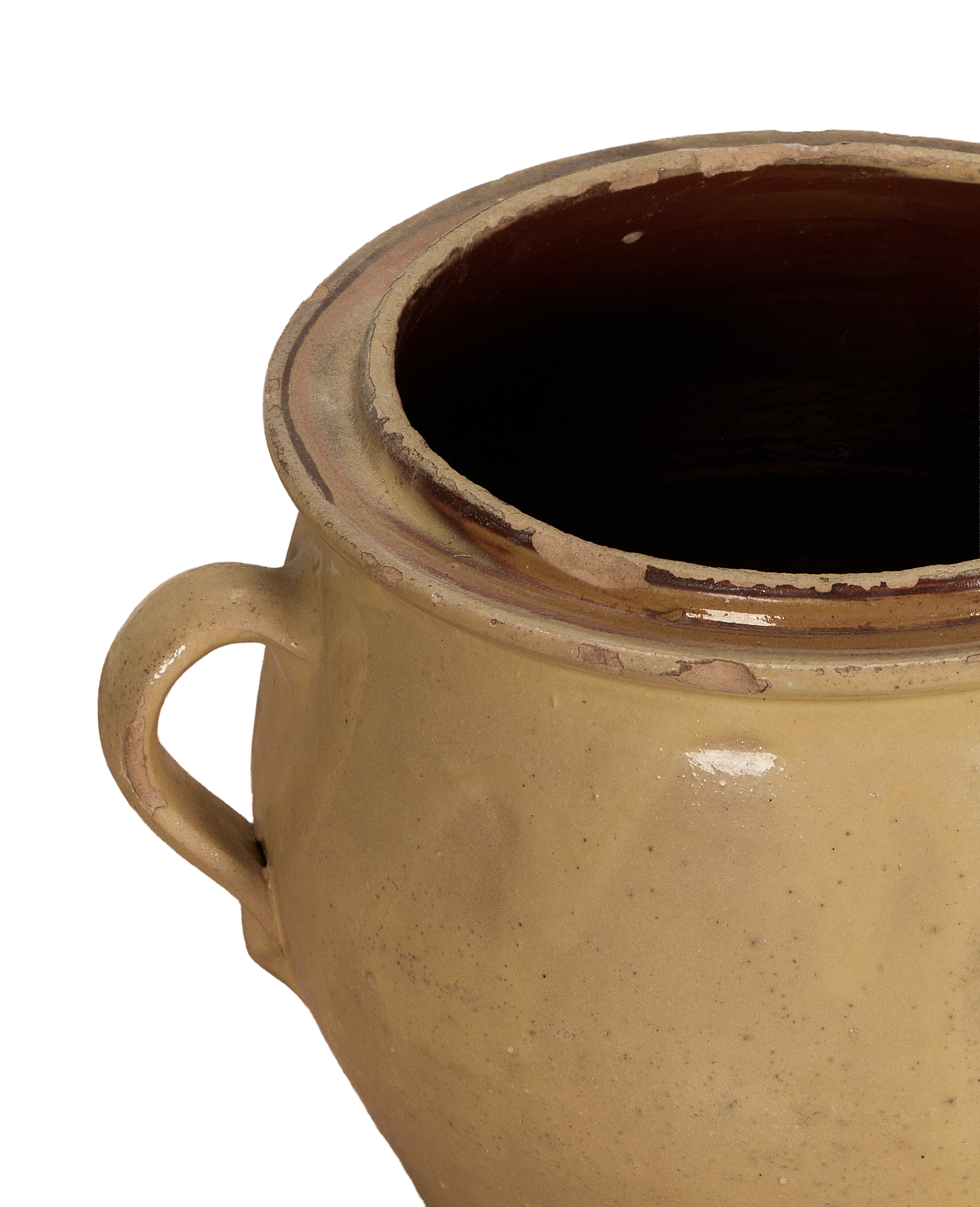 Close-up of antique French confit crock's yellow glazed rim and handle, showing age.