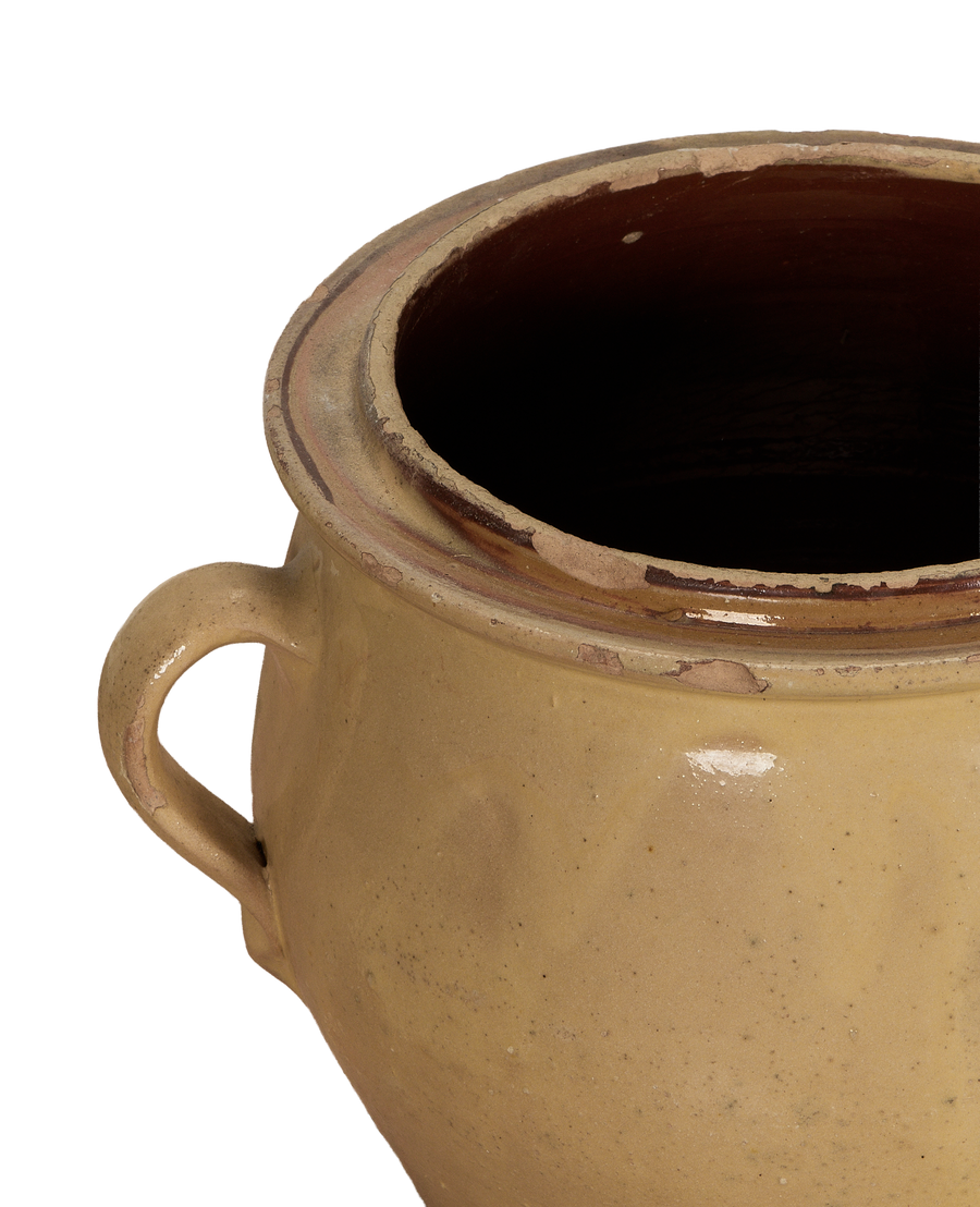 Close-up of antique French confit crock's yellow glazed rim and handle, showing age.