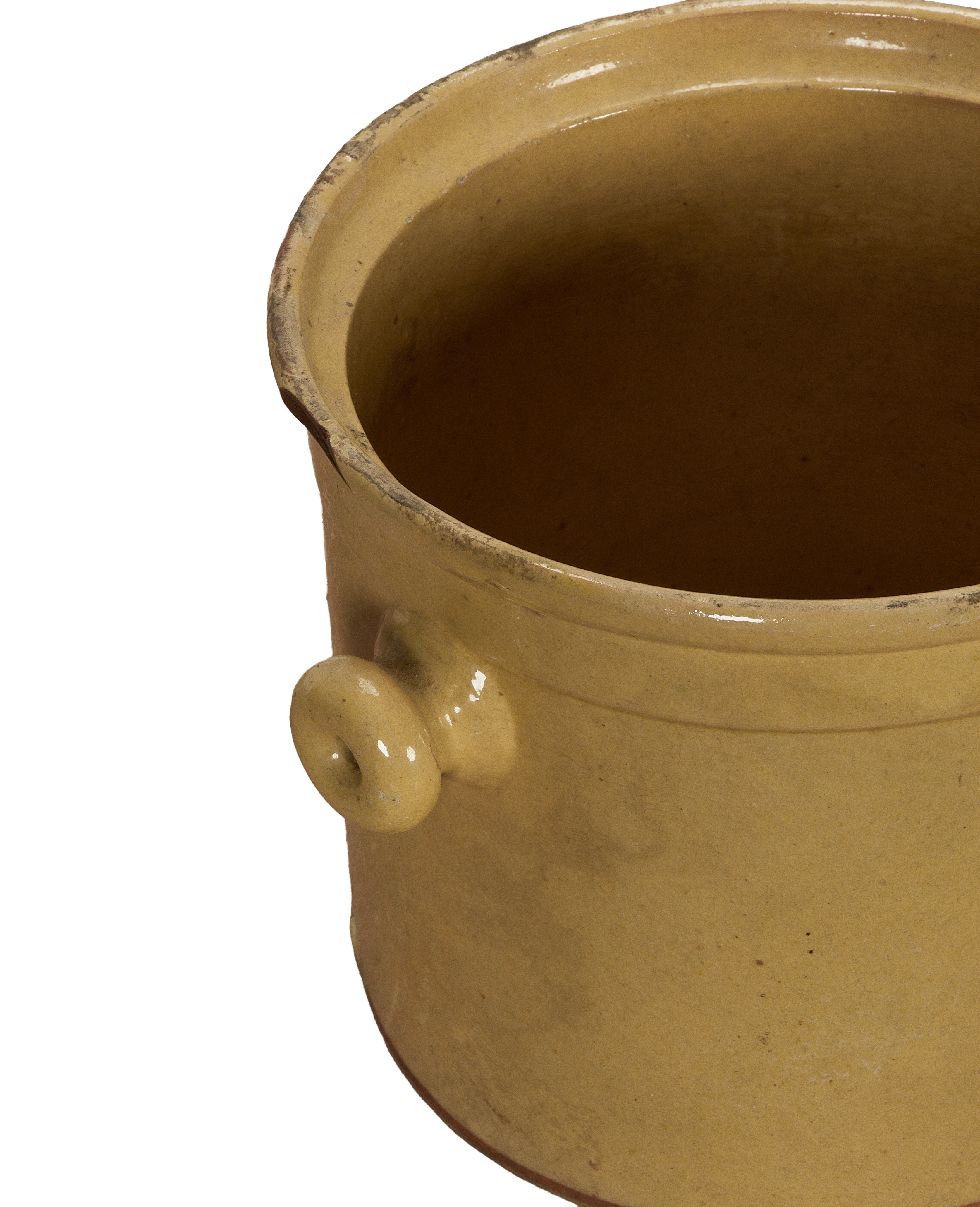 Antique French confit crock, close-up interior view with textured yellow glaze and side handle.
