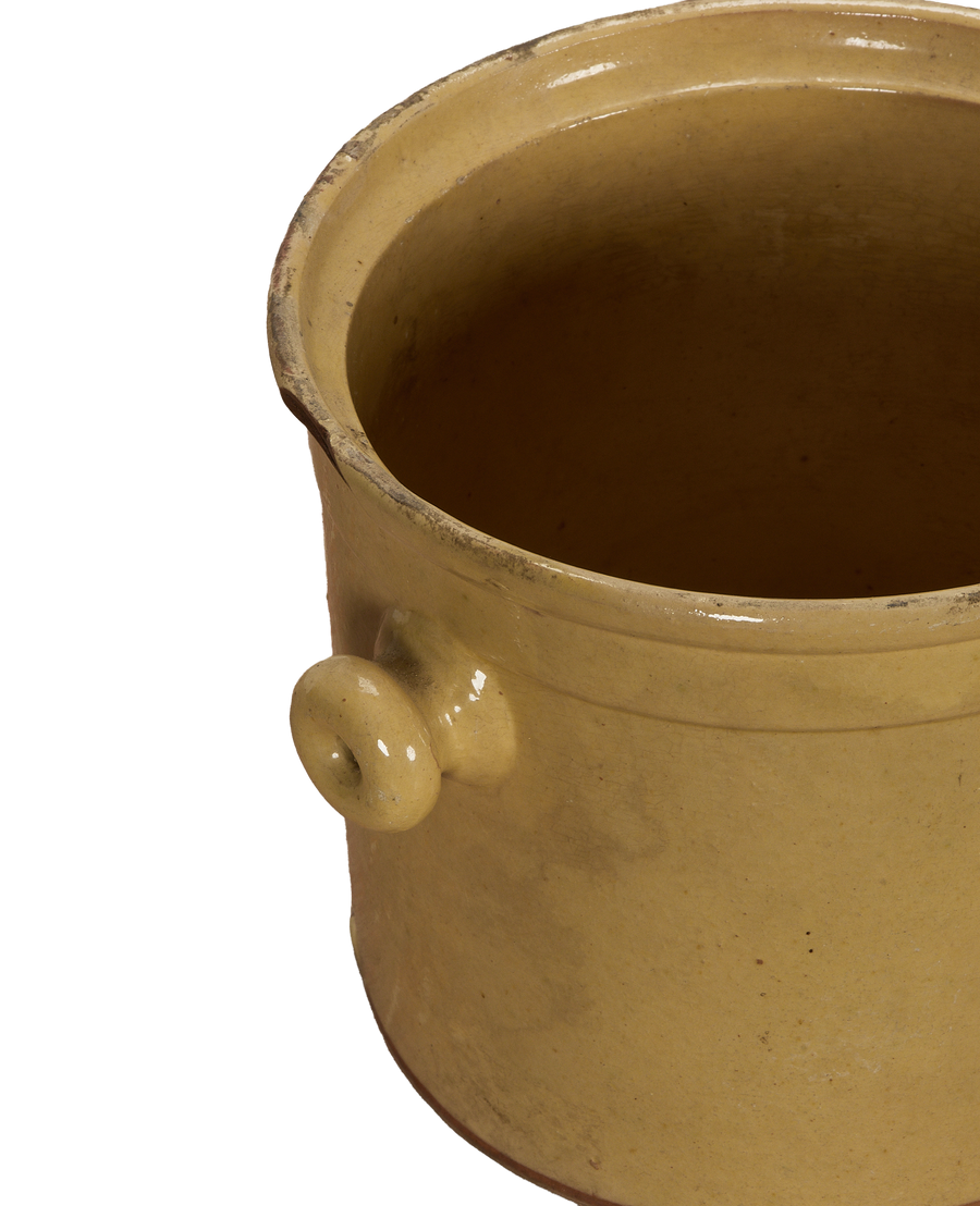 Antique French confit crock, close-up interior view with textured yellow glaze and side handle.