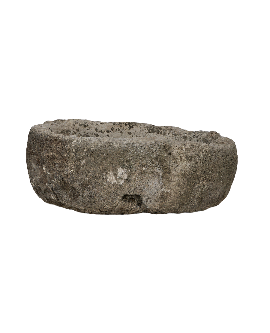 Vintage round Indonesian limestone trough, showing a side view of its worn, textured surface.