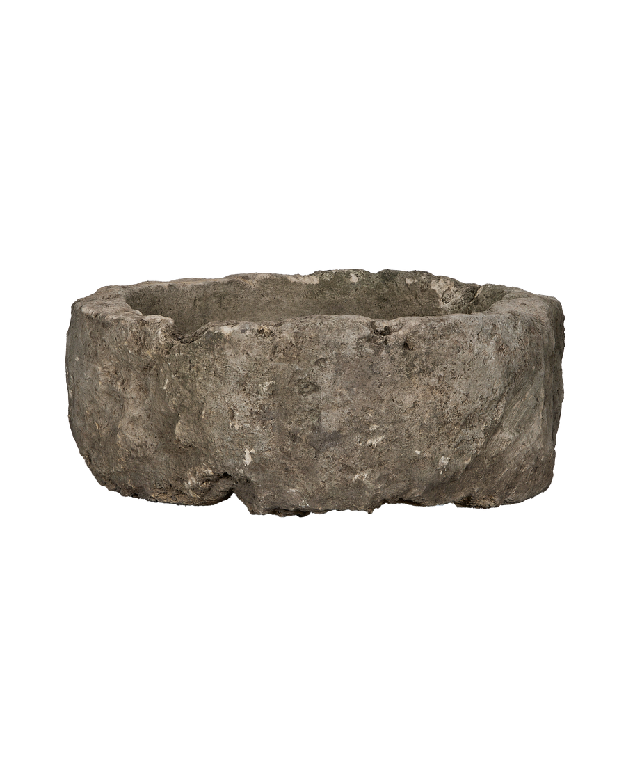 Vintage Indonesian round limestone trough, side profile, revealing rough natural texture.