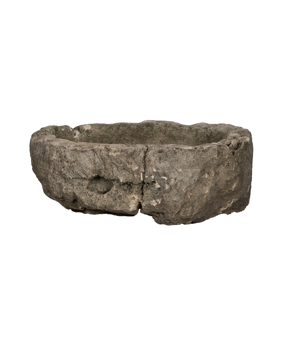 Vintage round limestone trough, showing a side view of rough-hewn texture and natural cracks.