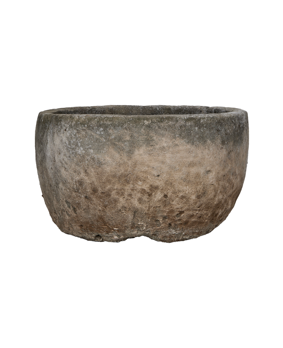 Vintage Indonesian limestone trough showcasing weathered texture and rounded shape from a side angle.