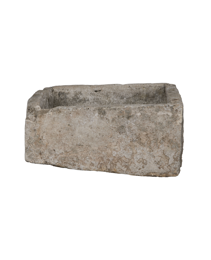 Vintage rectangular limestone trough, showcasing weathered stone texture and rough edges from a side angle.