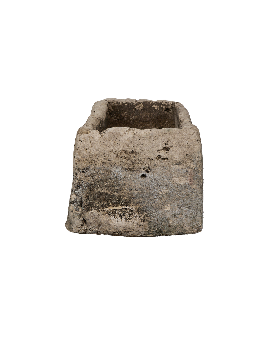 Vintage Indonesian limestone trough viewed from an angle, showcasing weathering and interior depth.