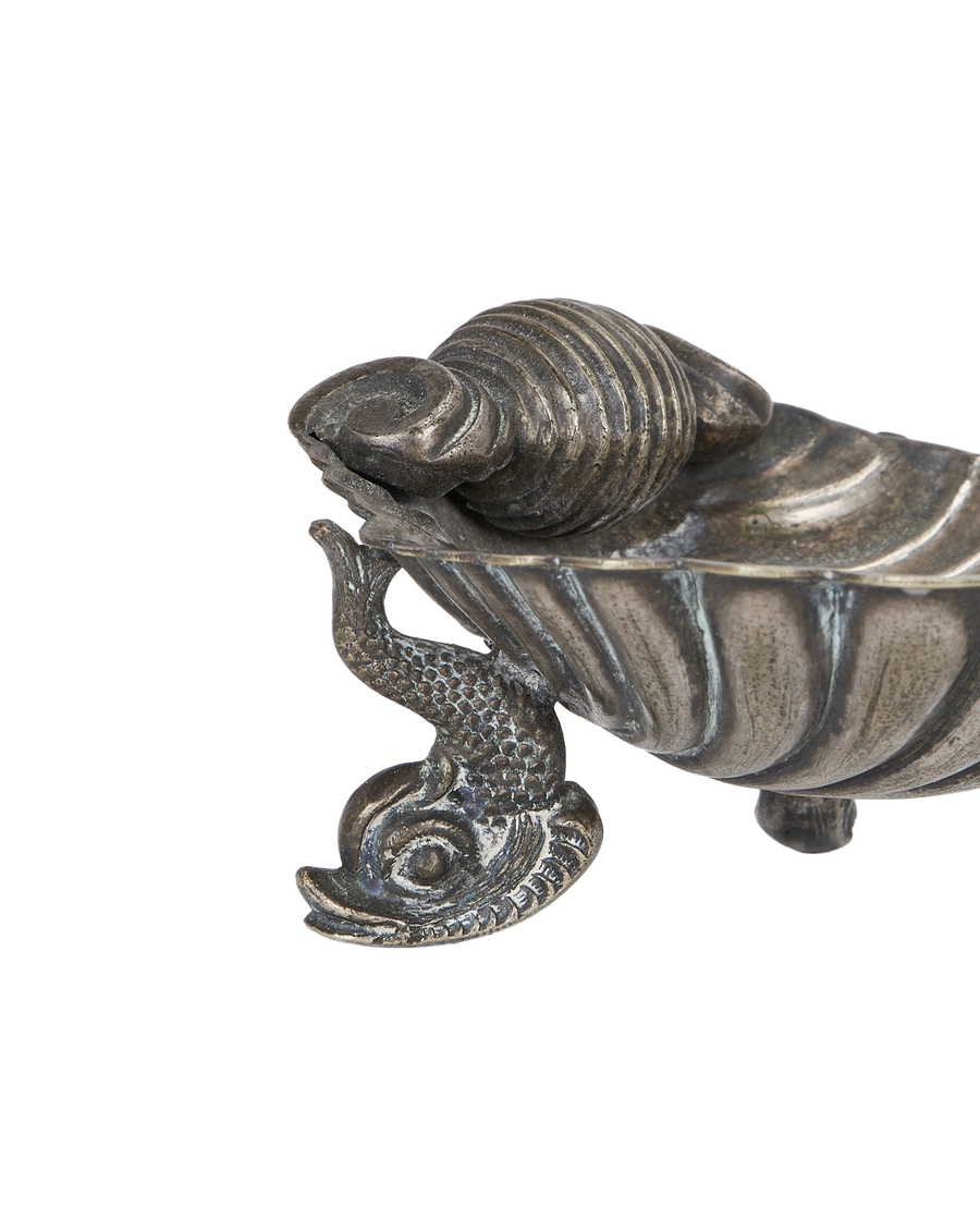 Close-up antique French brass shell ashtray showcasing aged patina and detailed dolphin feet.