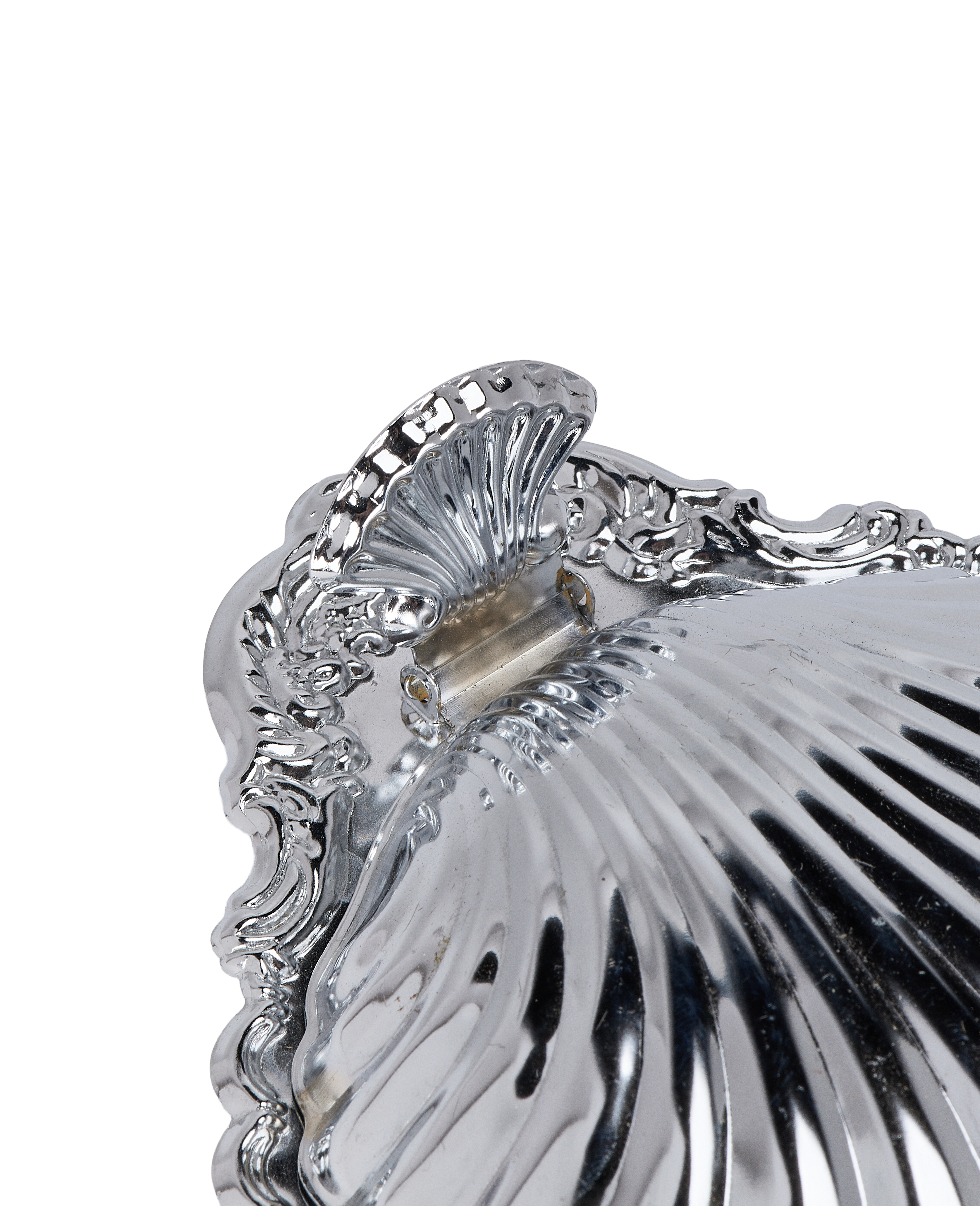 Close-up of vintage French steel butter dish hinge, showing ornate shell and scrolled details.