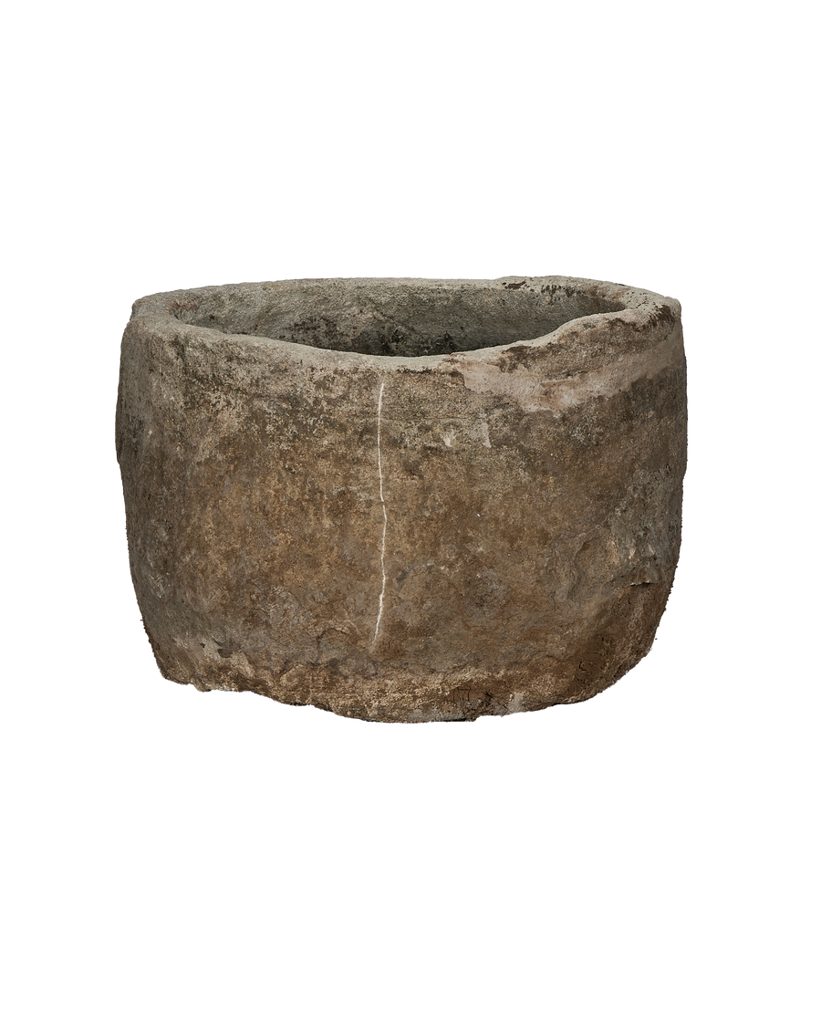 Vintage round limestone trough, full side view, showing weathered surface and a vertical crack.