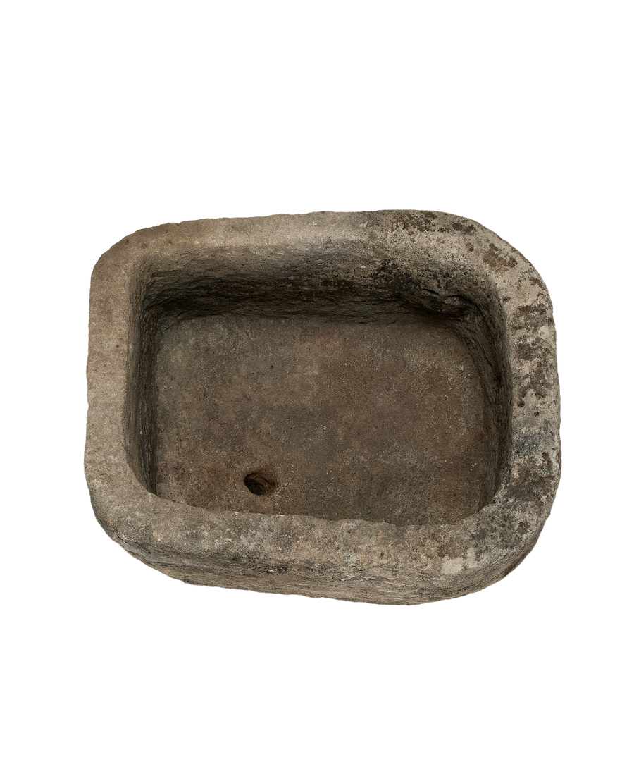 Vintage Indonesian oblong limestone trough, dark interior, showing drain hole and textured surface.