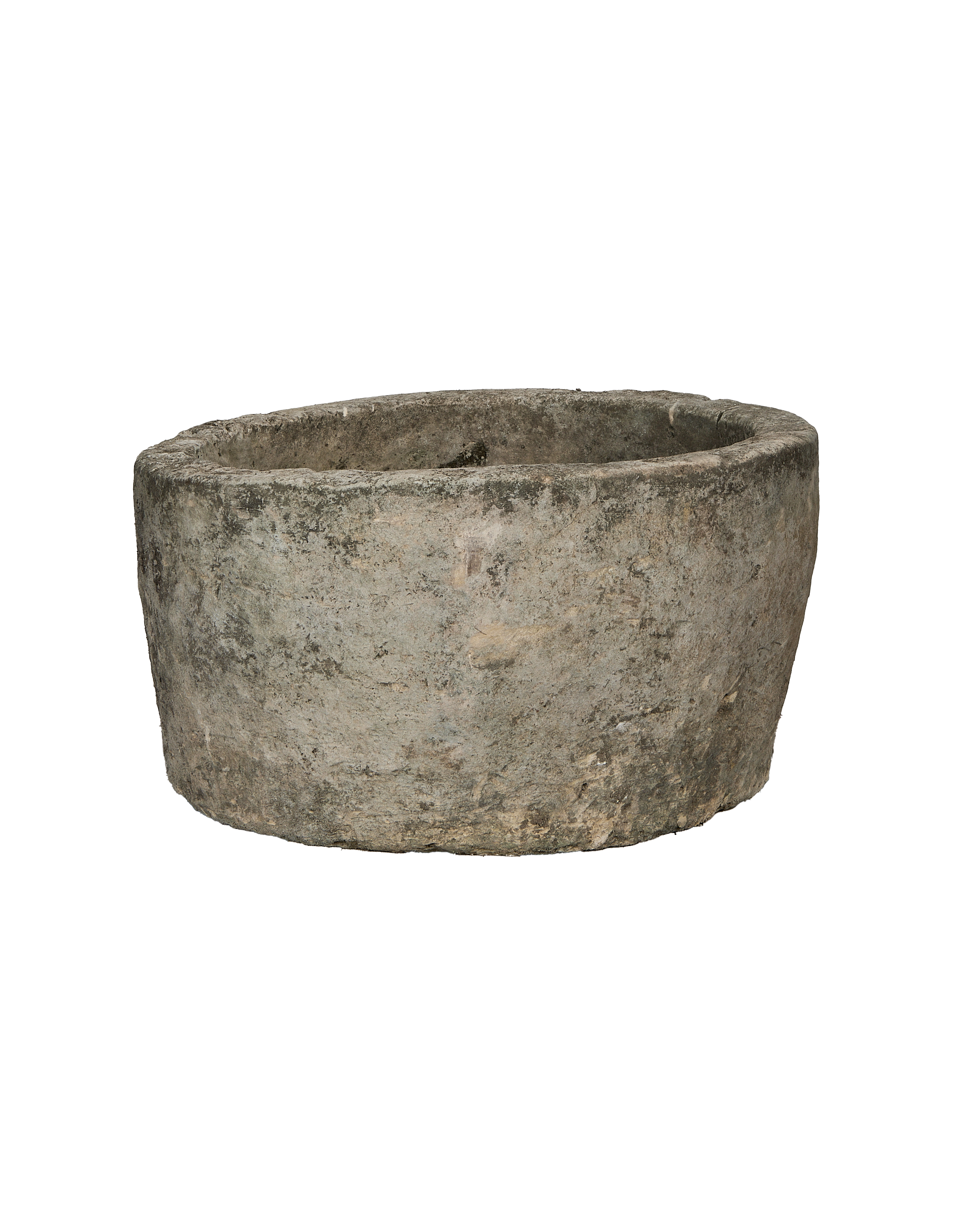 Vintage round, rough-textured Indonesian limestone trough showing weathered exterior from side angle.