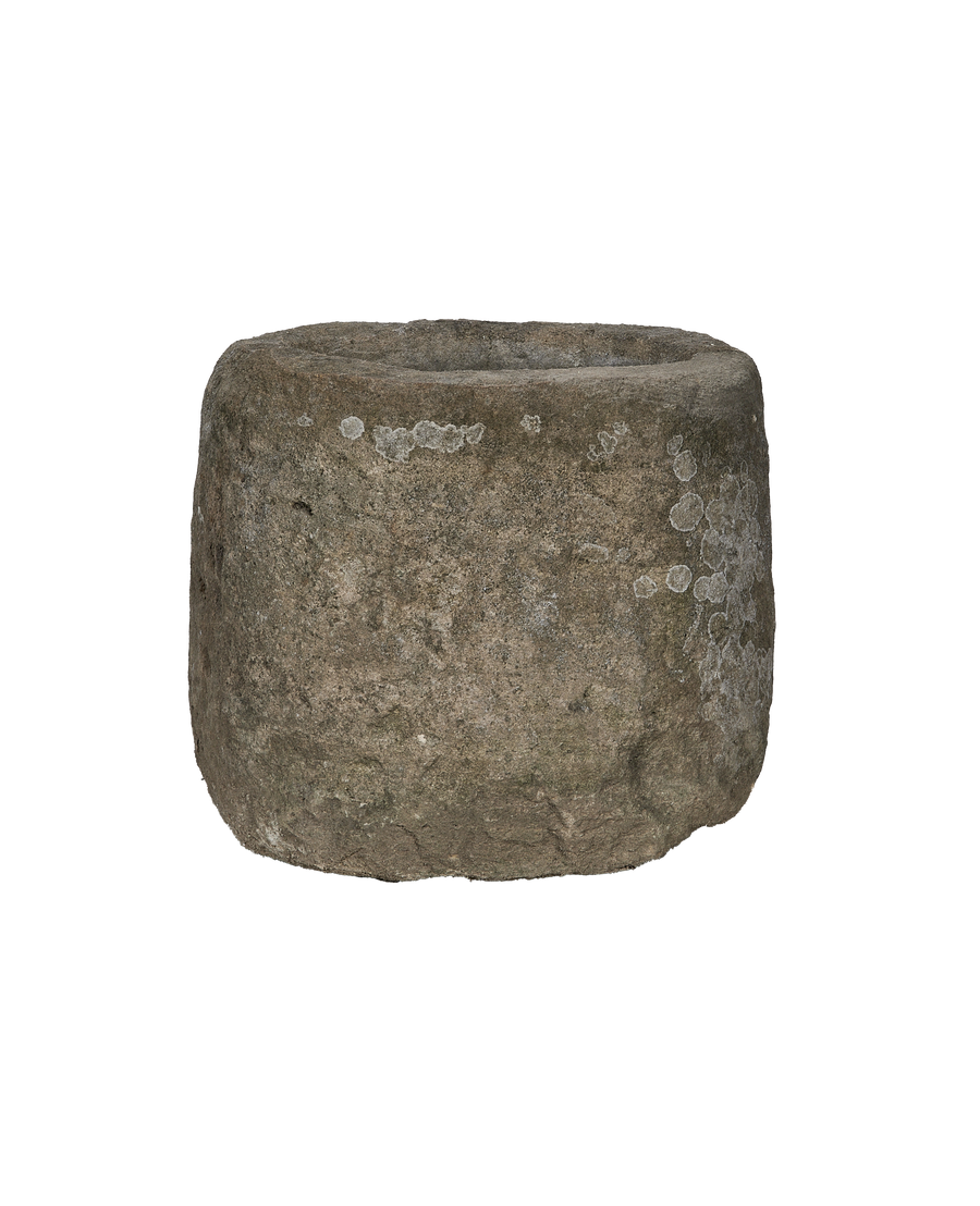 Vintage limestone trough from Indonesia, showing side view with rough texture and white lichen.