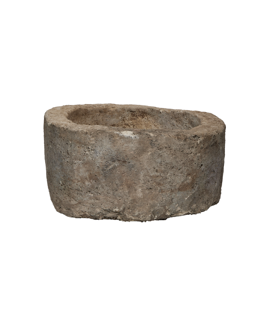 Vintage Indonesian limestone trough, round, showing weathered, rough texture from a side angle.