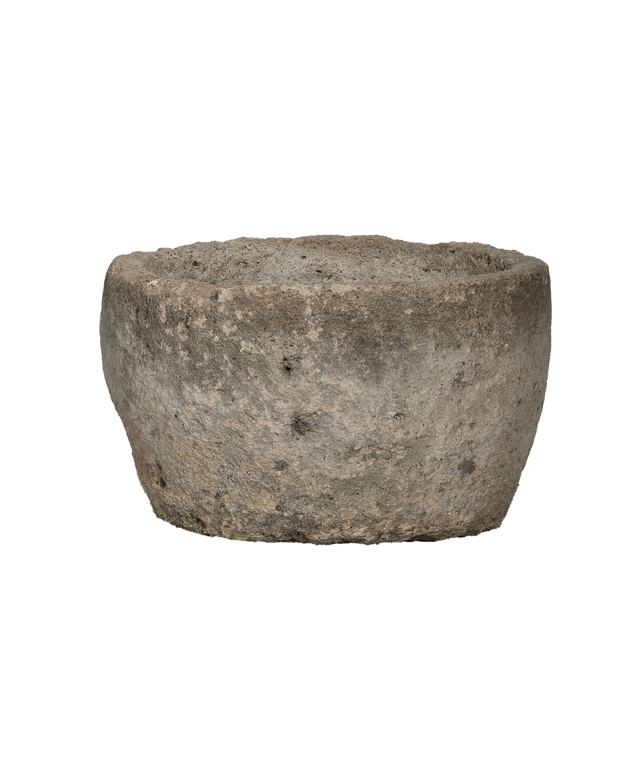 Vintage Indonesian round limestone trough, showing its aged, weathered surface and organic texture from a lower side angle.