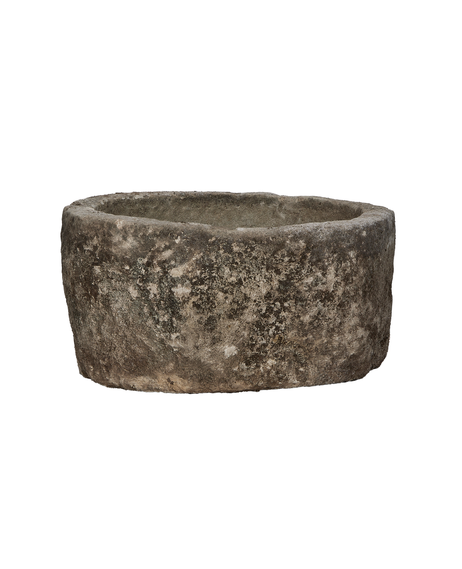 Vintage Indonesian limestone trough, round, showing weathered texture and natural imperfections, slightly angled view.