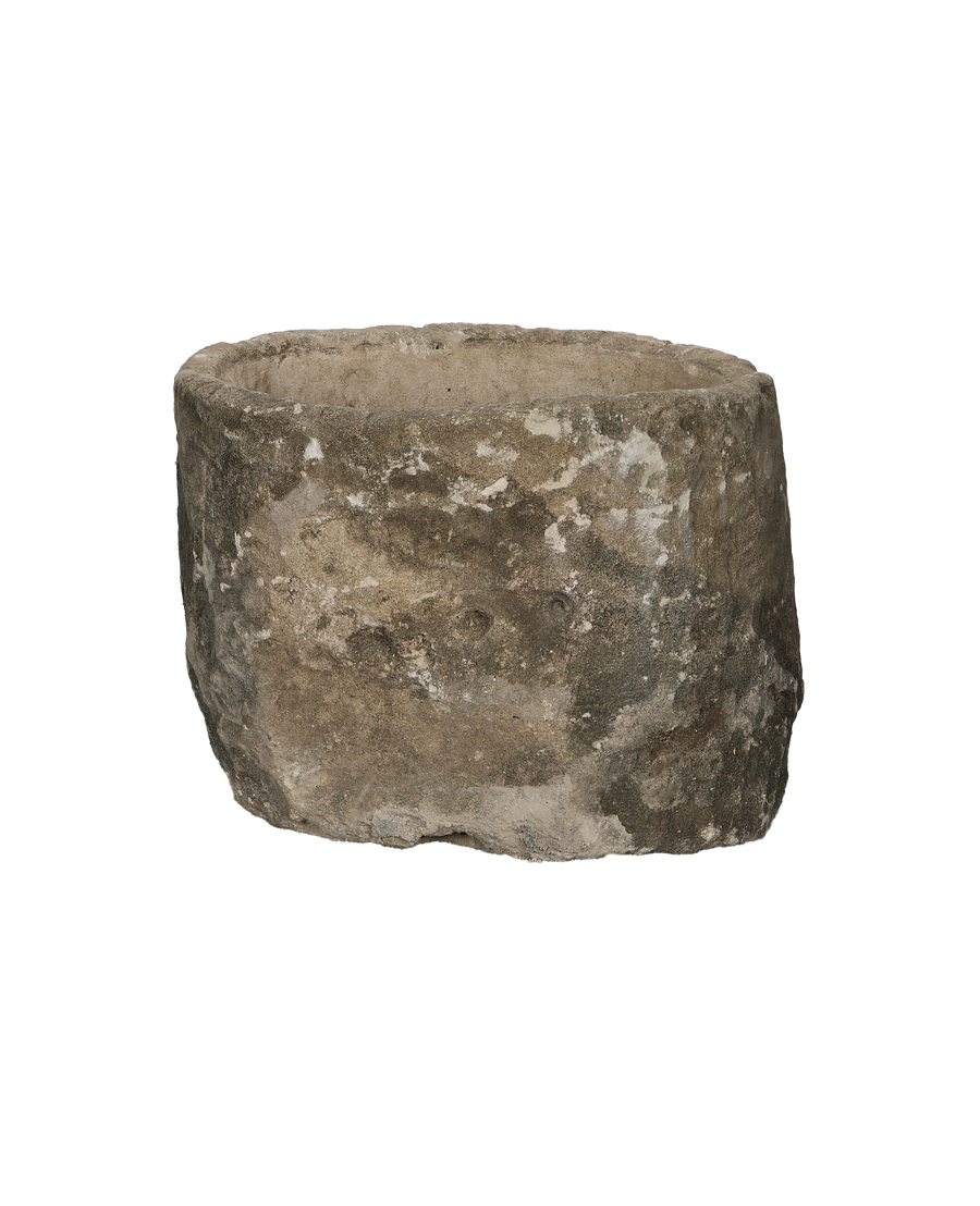 Vintage round limestone trough, side view revealing rustic texture and uneven rim.