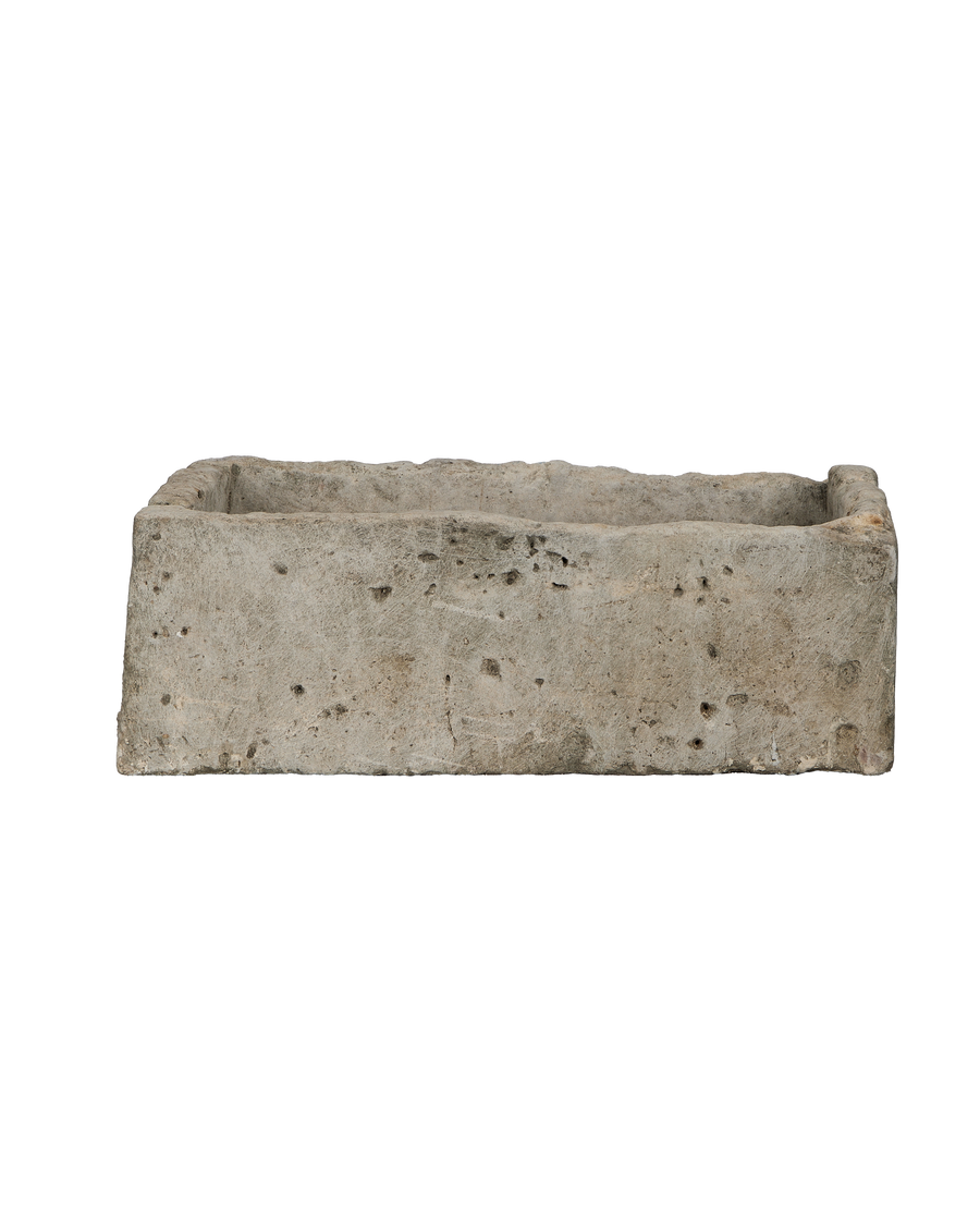 Vintage Indonesian rectangular limestone trough, showing rough textured exterior and weathered condition from side angle.