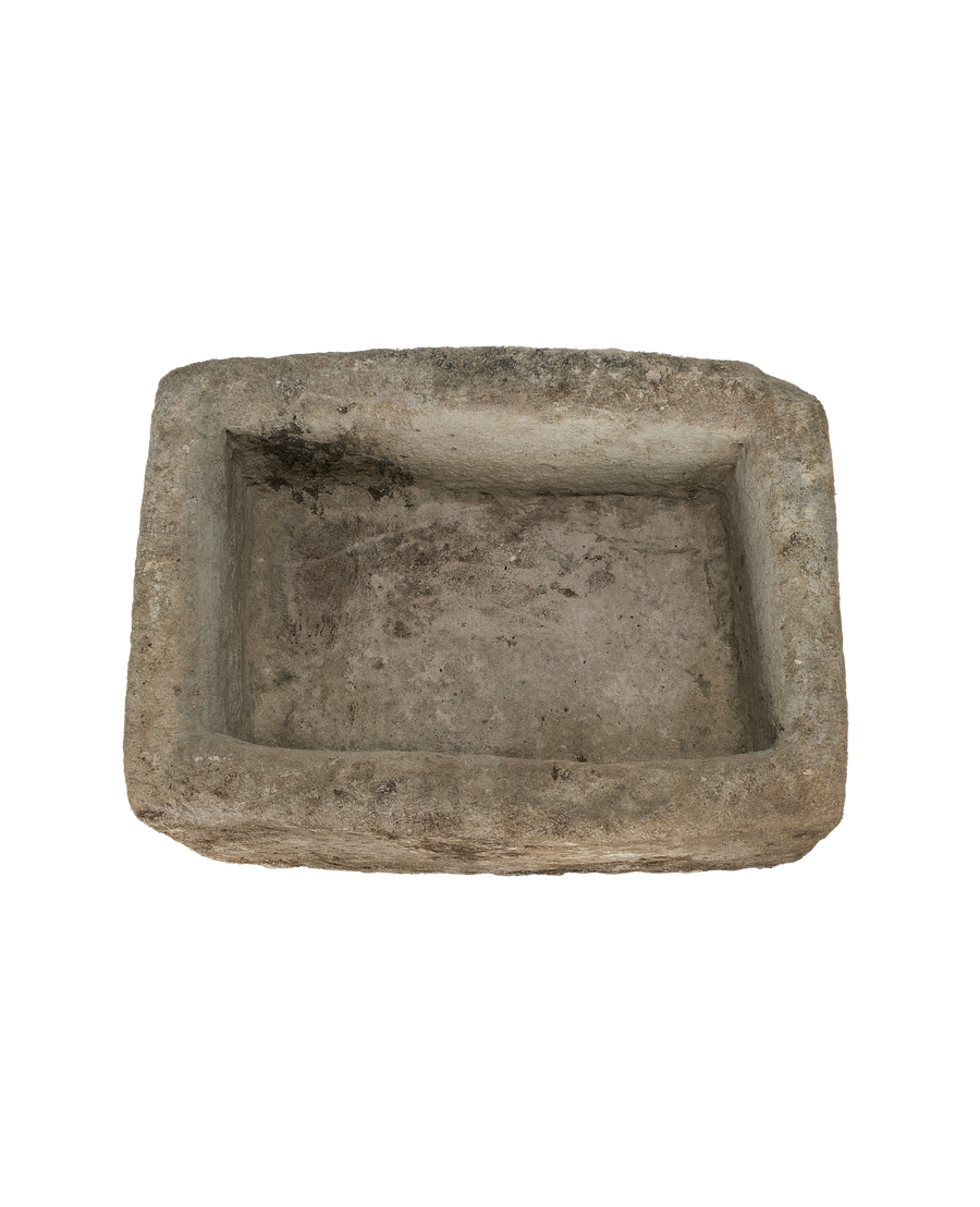 Vintage rectangular limestone trough, rustic texture, dark interior, top-down view.